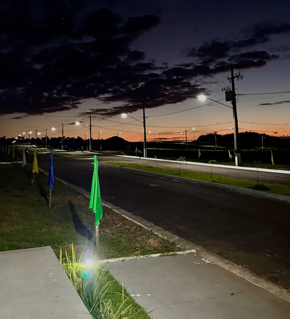 Ruas do loteamento com postes acesos ao anoitecer